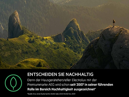 Person auf Felsen in grüner Berglandschaft mit Weitblick.